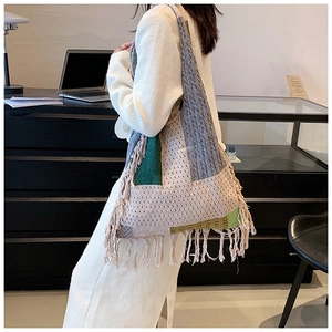 Detailed close-up of Bohemian knitted tote bag with fringe tassels and woven strap