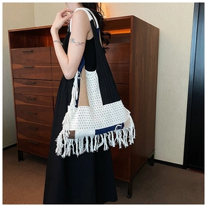 Detail of bohemian knitted tote bag featuring color-block design and white fringe trim