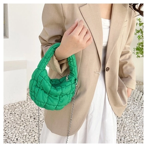 Detalle del bolso acolchado verde brillante con cadena metálica y textura acolchada