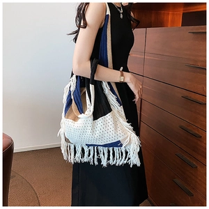 Detail of bohemian knit tote bag with colorful patchwork and long white fringe tassels