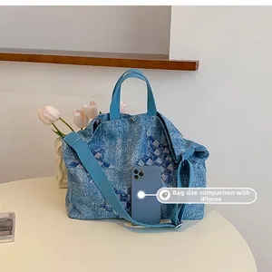 Denim tote bag with star pattern compared to iPhone for size reference on cream table