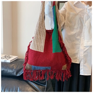 Detail of colorful patchwork knit tote bag with long red tassels and soft textured weave