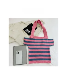 Detail of knit shoulder bag in striped T-shirt shape on soft bedroom setting