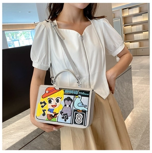 Détail du sac gris avec broderies de dessins animés colorés et écussons de street art