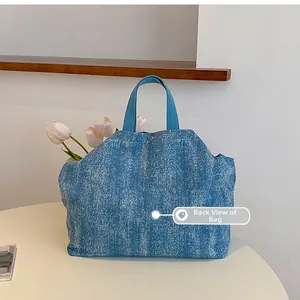 Close-up of the back of this large blue denim tote bag with sturdy handles and metal snap