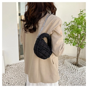 Detalle de bolso nube negro acolchado con cadena plateada fina y textura suave tipo puff