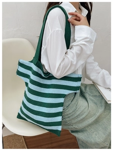 Detail of forest green and light blue striped knit shoulder bag on a model