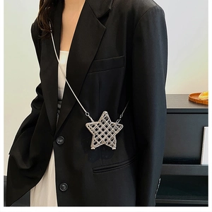 Chic silver star-shaped metal mesh mini bag with chain strap styled on a black suit blazer