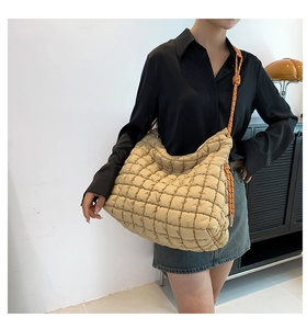 Gros plan d'un sac cabas matelassé beige avec une bandoulière en corde tressée orange et noir