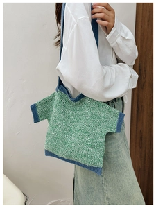 Detail of a green and white knitted shoulder bag in a unique mini T-shirt shape with trim