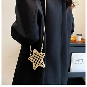 Star shaped gold metal mesh crossbody bag with chain shown on a black blazer