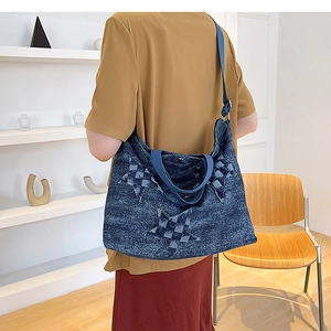 Detail of large denim tote bag with star patchwork and blue wide shoulder strap