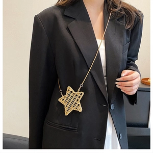 Detail of a shiny gold star-shaped mini crossbody bag with a metal mesh texture and chain