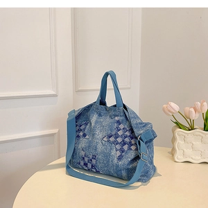 Macro view of denim tote bag with blue checkerboard star embroidery and wide strap