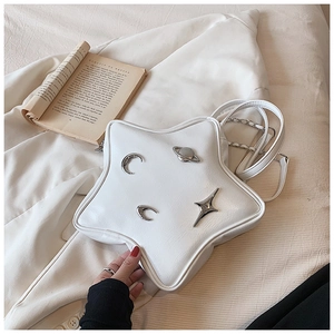 Macro shot of star-shaped white PU leather bag with metallic moon and star charms
