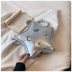 Detail of silver star-shaped crossbody bag with metallic celestial charms on white background