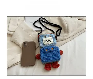 Close-up of handmade crochet robot phone bag featuring blue knit textures and button eyes