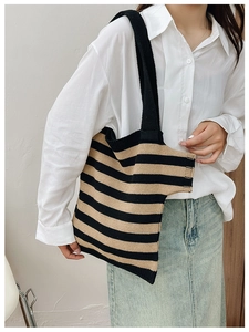 Close-up of a striped knit shoulder bag with soft texture and wide strap on a model