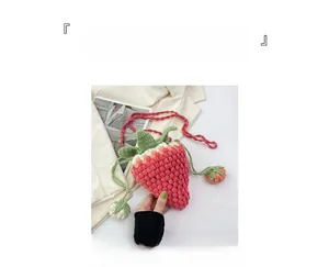 Detail of pink handmade crochet strawberry crossbody bag with green leaf accents and strap