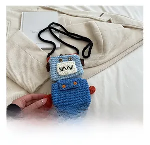 Detailed macro view of a handmade blue crochet robot shoulder bag on white fabric
