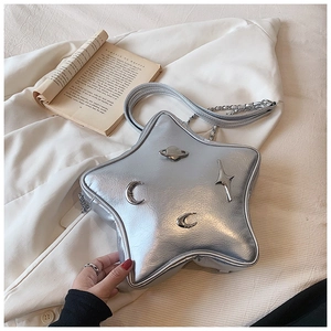 Detail of silver star-shaped shoulder bag featuring saturn logo and cosmic charms