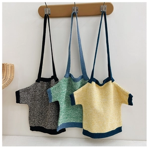 Three creative T-shirt shaped knitted shoulder bags in various colors on wooden hooks