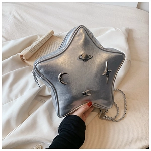 Detail of silver star-shaped crossbody bag with celestial moon and saturn metal badges