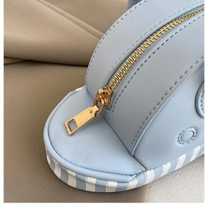 Detail of light blue crossbody bag featuring gold zipper and textured leather finish