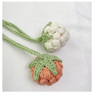 Detailed close-up of handmade crochet fruit charms with green leaf accents and woven lanyards