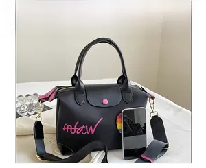 Close-up of black handbag with pink afaw text and smartphone for size comparison