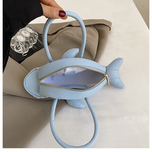 Detailed top view of a shark-shaped light blue handbag showing zipper and interior space