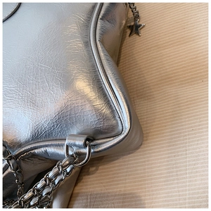 Detailed close-up of metallic silver star-shaped bag with chain strap and pendant