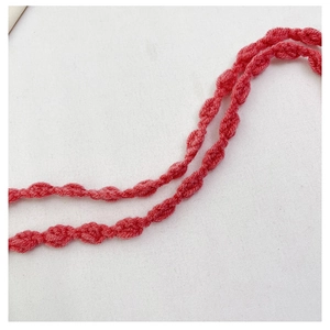 Close-up of handmade coral pink crochet strap showing detailed knotted knit texture