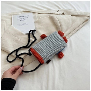 Detail of handmade crochet crossbody bag with grey-blue and orange knit animal design