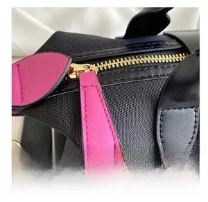 Detail showing smooth golden metal zipper and leather puller on the black nylon handbag