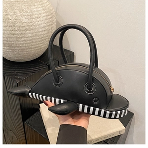 Close-up of a unique whale-shaped crossbody bag with black stripes and metal zipper details