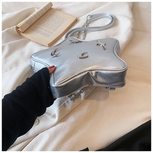 Detail of silver star-shaped crossbody bag with metallic moon and star relief accents