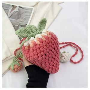 Close-up of strawberry crochet crossbody bag with chunky knit texture and leaf details