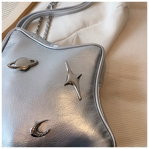 Detail of silver star-shaped bag with metallic planet ornaments and chain strap