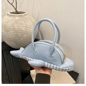 Detail of light blue whale shaped handbag with striped base and dual top handles