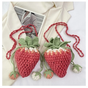 Close-up of handmade crochet strawberry crossbody bags with green leaf details