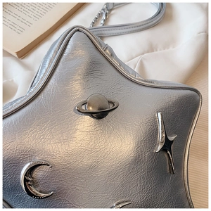 Detail of silver star-shaped shoulder bag with metallic texture and Y2K planetary charms