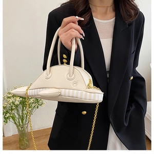 Close-up of shark-shaped white leather crossbody bag with golden chain and striped base
