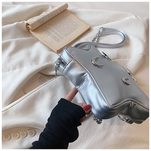 Detailed macro view of silver metallic crossbody bag featuring three moon-shaped charms
