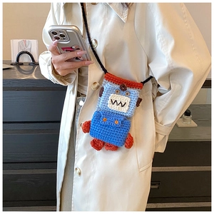 Detail of hand-knitted robot-shaped crossbody phone bag on a beige trench coat