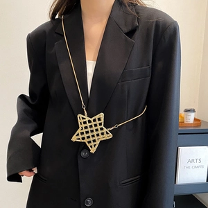 Golden star shaped metal crossbody chain accessory worn over a black blazer for styling