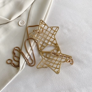Gold star-shaped hollow metal mini crossbody bag with sleek snake chain on beige fabric