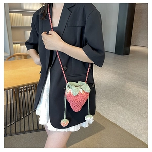 Detail of handmade crochet strawberry crossbody bag with green leaf drawstring and mini charm