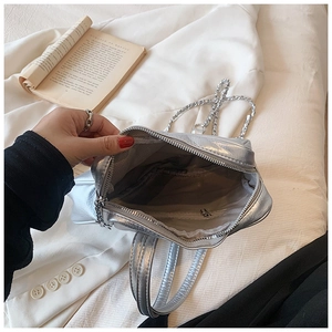 Silver metallic backpack showing interior storage space with zipper pocket and chain strap