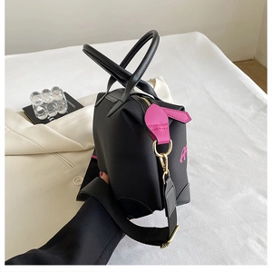 Detail of black canvas tote bag with pink leather accents and adjustable wide shoulder strap